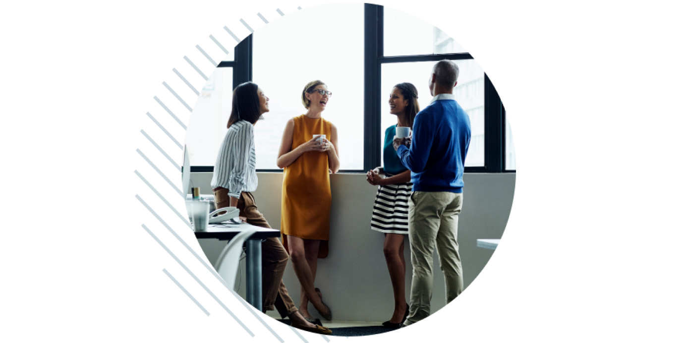 A diverse group of people in an office engaged in conversation.