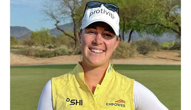 Jennifer Kupcho on golf course, wearing yellow vest with Empower logo.