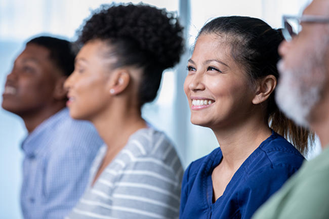 several multi-racial faces shown sitting together, smiling